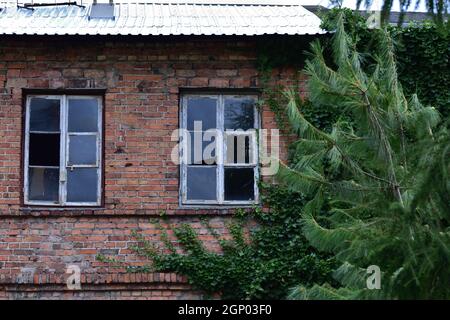 Broken windows in a house and a run-down house. Ruin. Stock Photo