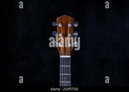 acoustic guitar head with chrome tuning pegs and fretboard on isolated black background Stock Photo