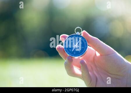 Young man on an adventure is holding a compass in his hand for finding is route Stock Photo