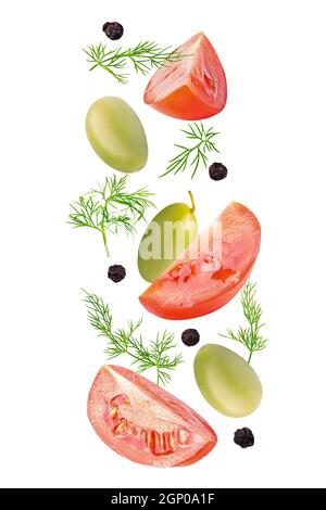 Isolated vegetables. Mixed tomatoes, dill, green olives and black pepper corns in the air isolated on white with clipping path as package design eleme Stock Photo