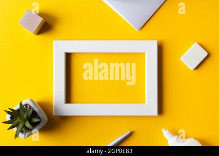 Creative workplace or workspace with bright yellow surface, blank photo frame, office accessories, top view, space for text. Stock Photo