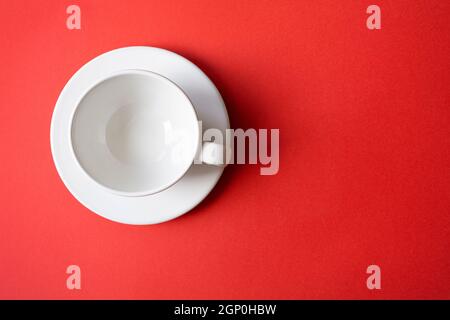 Simple flat lay composition with empty white ceramic cup, mug, bowl on a plate with bright red background, top view, space for text Stock Photo