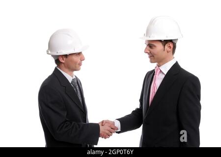 Two young Engineers closing a deal, isolated in background Stock Photo