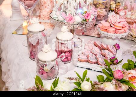 Delicious desserts at the wedding candy bar in the buffet area: cookies covered with icing, decorated with angels, cameo, sugar rosebuds and silver dy Stock Photo