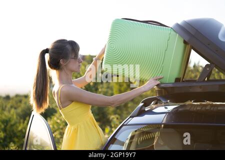 Young woman putting green suitcase 