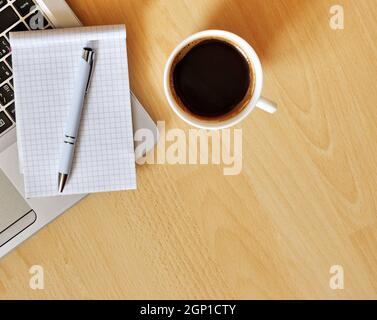 Laptop with coffee cup, notebook and pen on wooden background, concept for home office. Business concept. Work from home. desk office with laptop. Stock Photo