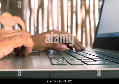 hands of an unidentifiable person working on his laptop on a sunny day Stock Photo