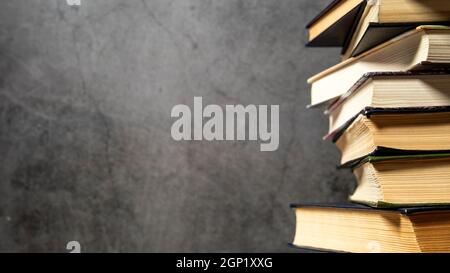Old books are stacked on top of each other, collection of old books on a dark background. Side view with place for text. Stock Photo