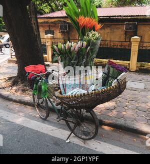 Hanoi, Vietnam - Oct 3, 2013. Selling flowers on bicycle in Hanoi street. Hanoi, located on the banks of the Red River, is one of the most ancient cap Stock Photo