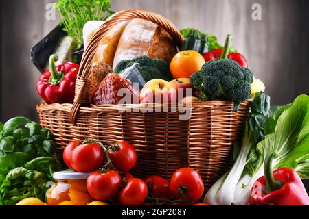 Wicker basket with assorted grocery products including fresh vegetables and fruits Stock Photo