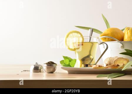 Cup of green tea with ginger lemon and mint on wooden table with leaves, metal bowl on wooden table and white isolated background. Front view. Stock Photo