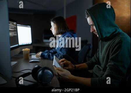 Male and female hackers works on computers in darknet, dangerous teamwork. Illegal web programmer at workplace, criminal occupation. Data hacking. Stock Photo
