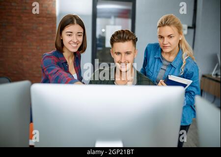 Smiling IT specialists works on computers in office. Web programmer or designer at workplace, creative occupation. Modern information technology, corp Stock Photo