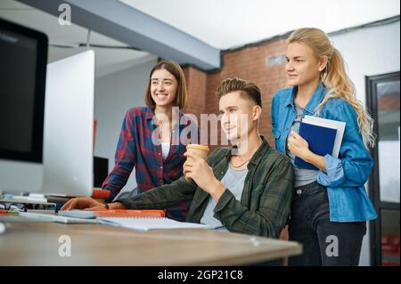 Smiling IT specialists works on computers in office. Web programmer or designer at workplace, creative occupation. Modern information technology, corp Stock Photo