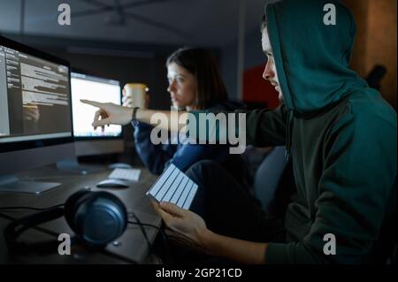 Male and female hackers works on computers in darknet, dangerous teamwork. Illegal web programmer at workplace, criminal occupation. Data hacking, cyb Stock Photo