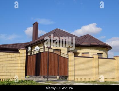 Decorative metal on the roof of a brick house. Fence made of corrugated metal Stock Photo