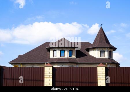 Decorative metal on the roof of a brick house. Fence made of corrugated metal Stock Photo