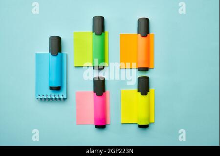 Colorful permanent markers and notepads on blue background. Office stationery supplies, school or education accessories, writing and drawing tools Stock Photo