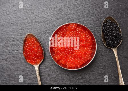 caviar of paddlefish fish and red chum salmon caviar in a spoon, black background, top view Stock Photo