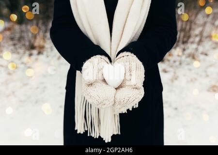 Snow heart snowball in girl gloved hands. Blurred background. High quality photo Stock Photo