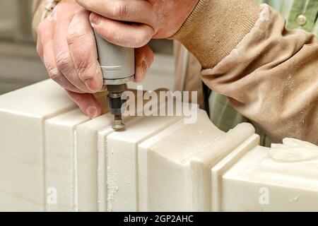 Closeup hand of anonymous craftsman using electric too to grind plaster ornament in workshop Stock Photo