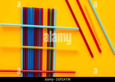 Multi-colored cocktail tubes lie on a yellow background Stock Photo