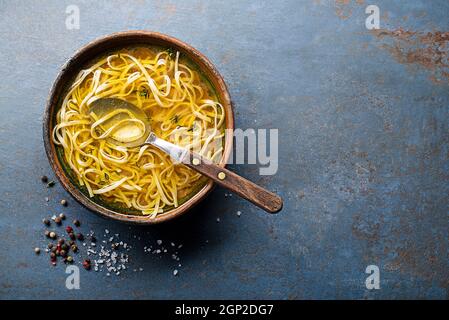 Tasty meat broth soup with herbs and noodles in a bowl closeup Stock Photo