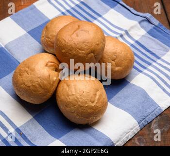 baked round small buns on a brown wooden table, close up Stock Photo