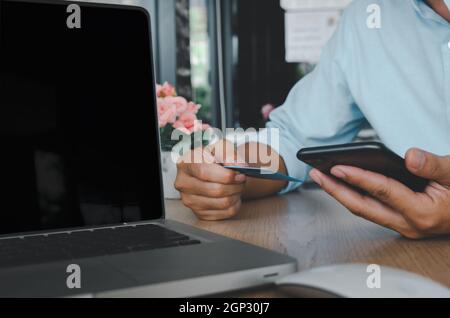 business man hand using mobile smart phone and credit card  with computer laptop on table.Shop online and make payment transactions business concept Stock Photo
