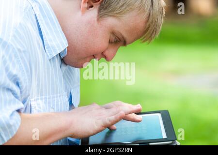 Close up portrait of handicapped boy outdoors with digital tablet. Stock Photo