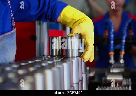 Preparation of finished bearings for conservation and packaging. Grease for bearing production. Hand in a yellow protective glove. Out focus. Heavy in Stock Photo