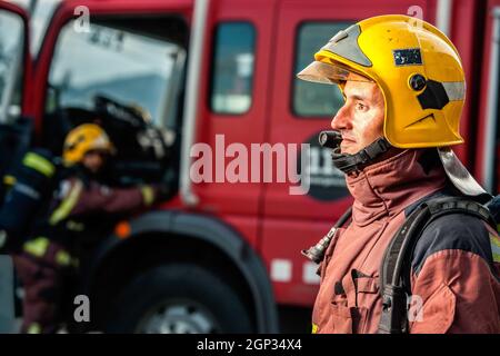 Close up portrait of Fireman staring at danger in front of fire truck. Stock Photo