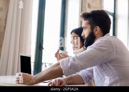 A man and a woman work together on a laptop. They are discussing something for their apartment. They are looking for something important on the Intern Stock Photo