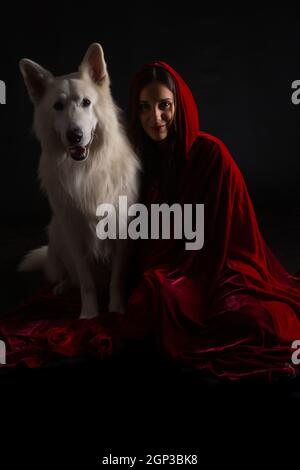 Woman wearing a red hood posing in studio with her dog Stock Photo