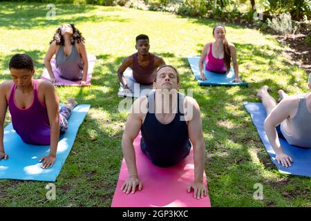 Group of diverse female and male people practicing yoga outdoors Stock Photo