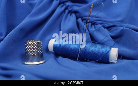 Thimble and Blue Thread on Blue Fabric Stock Photo