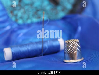 Thimble and Blue Thread on Blue Fabric Stock Photo