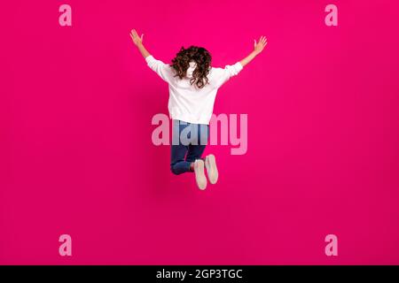Back rear view full body photo of young girl jumper hands up spine anonymous isolated over pink color background Stock Photo