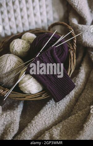 Hand knitting sock with needles and yarn balls in a basket.  Concept for handmade and hygge slow life. Stock Photo