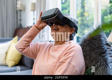 Happy mixed race senior woman wearing vr headset and having fun Stock Photo