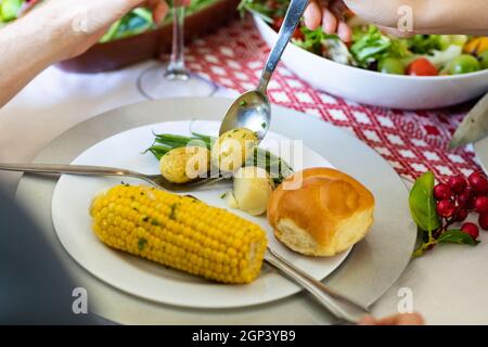 Hands of caucasian men putting potatoes on plate at christmas table Stock Photo