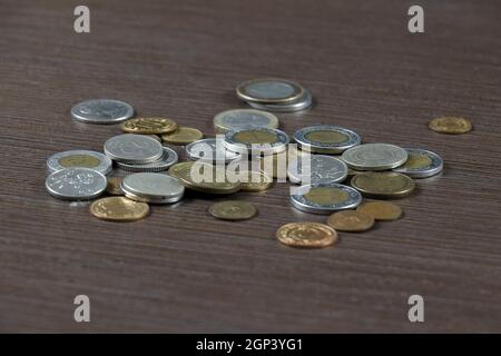 Silver and bronze metal money several international currencies pile on wooden background Stock Photo