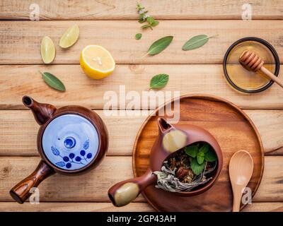 Herbal tea pot with fresh herbs sage ,peppermint , dried chrysanthemum and lime slice on rustic wooden background. Stock Photo