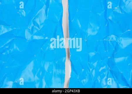 crumpled blue cardboard sheet of paper on white background, a4 sheet torn in half Stock Photo