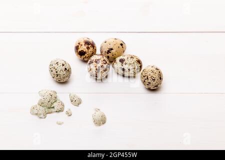 Several quail eggs on a white wooden background. Top view, close-up. Stock Photo