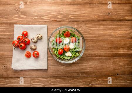 Red juicy fresh cherry tomatoes on a green branch. Tomatoes with green arugula and quail eggs in a cup. Free space for text. Stock Photo