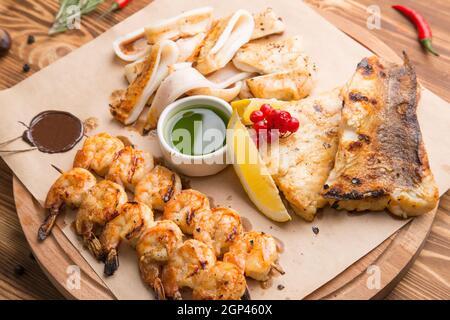 hot snacks from fish and seafood. Assorted fried seafood: fried squid rings with spices, baked fish fillets, grilled shrimp. Concept - menu for a rest Stock Photo