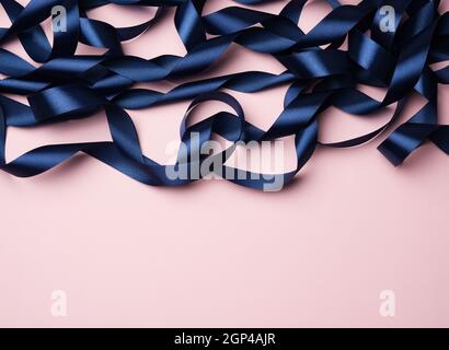 curled blue silk ribbon on a pink background, festive background, copy space Stock Photo