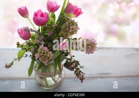 Composition with fresh spring flowers on gray wood, in background tender romantic pink bokeh with space for text. Short depth of field Stock Photo