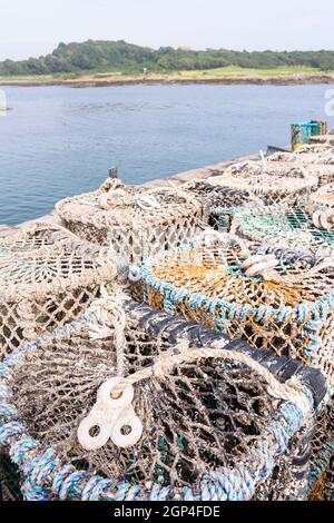 Traditional lobster cages sitting on a harbour beside the sea Stock Photo